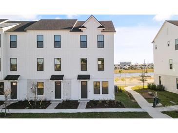 Three-story townhome with white siding, gray accents, and landscaping at 15100 Grove Lake Dr, Winter Garden, FL 34787