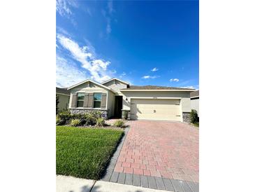 One-story house with a two-car garage, landscaping, and brick paver driveway at 17795 Blazing Star Cir, Clermont, FL 34714