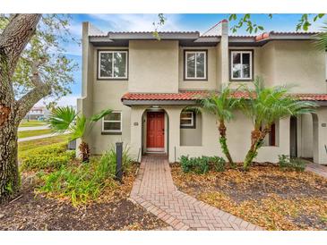 Charming townhome with a red tile roof, brick walkway, and lush tropical landscaping at 1007 Baseball And Boardwalk Ct, Kissimmee, FL 34746