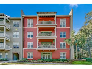 Three-story building with red exterior, balconies, and lush landscaping at 1410 Celebration Ave # 101, Celebration, FL 34747