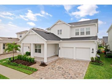 Two-story white house with gray roof, three-car garage, and landscaped front yard at 14255 Spring Garden Dr, Winter Garden, FL 34787