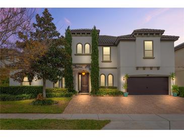 Two-story house with a white exterior, brown garage door, and a brick driveway at 16669 Varone Cove Ct, Winter Garden, FL 34787