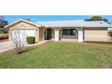 Charming single-story home featuring a well-manicured lawn and a welcoming front porch with brick accents at 2207 Winter Woods Blvd, Winter Park, FL 32792