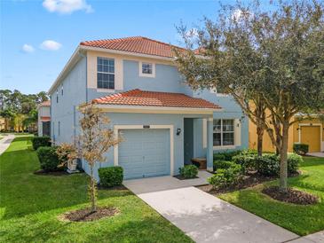 Two-story house with light blue exterior, tile roof, and landscaped yard at 2957 Beach Palm Ave, Kissimmee, FL 34747