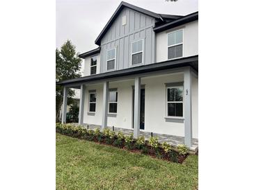 Two-story house featuring gray and white exterior, front porch, and landscaped lawn at 62 W Esther W St, Orlando, FL 32806