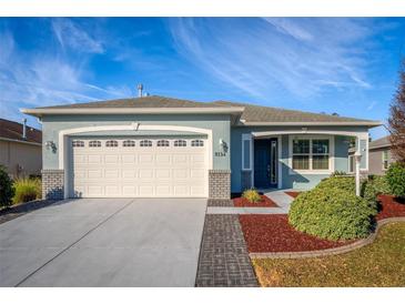 One-story house with light blue exterior, white garage door, and landscaped yard at 8134 Sw 78Th Terrace Rd, Ocala, FL 34476