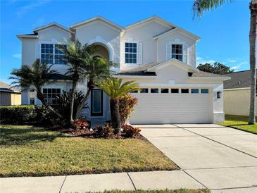 Two-story house with a three-car garage, landscaping, and palm trees at 9657 Pacific Pines Ct, Orlando, FL 32832