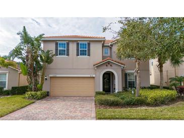 Two-story house with beige exterior, tan garage door, and landscaping at 12088 Uleta Ln, Orlando, FL 32827