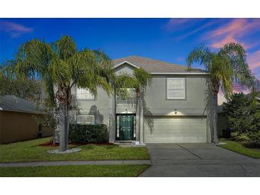 Two-story house with a green door, attached garage, and palm trees at 1633 Corner Meadow Cir, Orlando, FL 32820