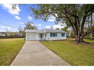 White house with blue accents, driveway, and large tree in the front yard at 277 Debary Dr, Debary, FL 32713