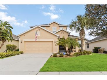 Two-story house with a large front yard, palm trees, and a two-car garage at 3019 Madelia Ln, Kissimmee, FL 34744