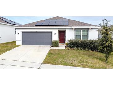 One-story house with gray garage door and solar panels at 1623 Aspen Ave, Davenport, FL 33837