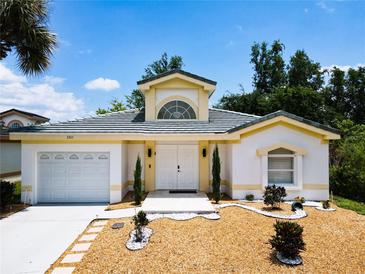 White house with gray roof, landscaping, and a two-car garage at 3211 Sunrise Walk, Kissimmee, FL 34747