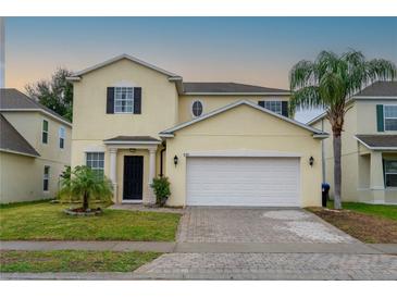 Two-story house with a two-car garage, paver driveway, and landscaping at 8747 Isla Bella Dr, Orlando, FL 32818