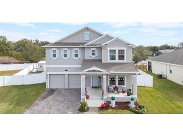 Two-story house with gray siding, two-car garage, and a covered front porch at 887 Panical Dr, Apopka, FL 32703