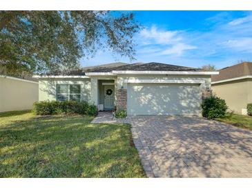 House exterior featuring a light-green color, a two-car garage, and a well-manicured lawn at 1420 Marsh Meadow Ln, Davenport, FL 33896