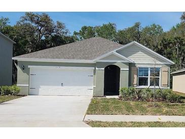 Charming one-story home with a two-car garage, manicured lawn, and fresh landscaping under a clear sky at 2114 Red Rock Rd, New Smyrna Beach, FL 32168