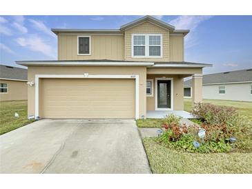 Two-story house with a beige exterior, two-car garage, and landscaping at 4269 Desert Rose Ave, Kissimmee, FL 34746