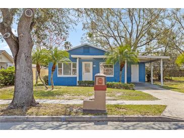 Charming blue home features a well-maintained front yard, palm trees, and a carport at 4900 Elese St, Orlando, FL 32811