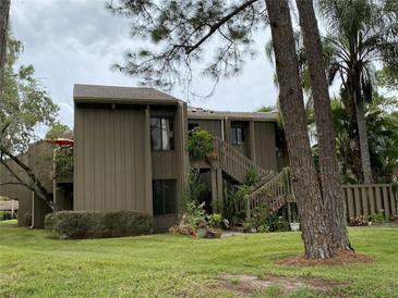 Two-story condo building with wood siding, landscaping, and stairs at 5302 Burning Tree Dr # F-02-2, Orlando, FL 32811