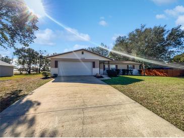 Tan single story home with attached garage and landscaped lawn at 1319 N Old Mill Dr, Deltona, FL 32725