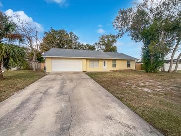 Cute yellow house with a white garage door and a spacious yard at 1350 Bailey Ave, Deltona, FL 32725
