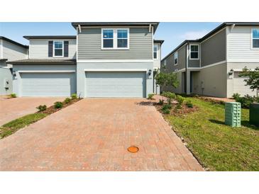 Charming townhomes with a brick driveway, attached garages, and a manicured lawn at 4329 Switchgrass Ln, St Cloud, FL 34772