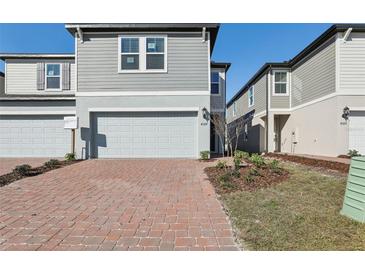 A gray two-story home boasts a spacious two-car garage and a charming brick driveway at 4329 Switchgrass Ln, St Cloud, FL 34772