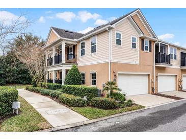 Tan townhome exterior with a walkway, landscaping, and attached garage at 1267 Marley Ln, Winter Springs, FL 32708