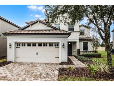 Two-story house with a beige exterior, a three-car garage, and a landscaped front yard at 1498 Moon Valley Dr, Davenport, FL 33896