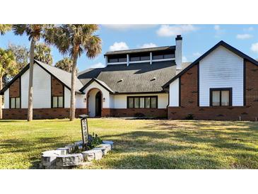 Two story home with brick and white siding, a large yard and palm trees at 2305 Leeward Cv, Kissimmee, FL 34746