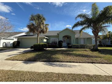 Single-story house with a green facade, attached garage, and palm trees at 3027 Eagle Lake Dr, Orlando, FL 32837