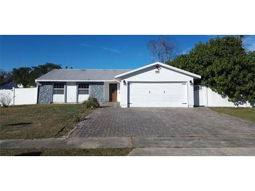 Ranch style home with paved driveway, two-car garage, and landscaped yard at 7852 Murcott Cir, Orlando, FL 32835