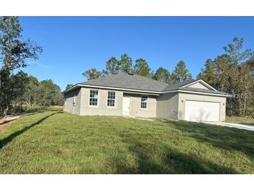 One-story home with gray siding, attached garage, and grassy yard at 8944 Sw 128Th Pl, Ocala, FL 34473