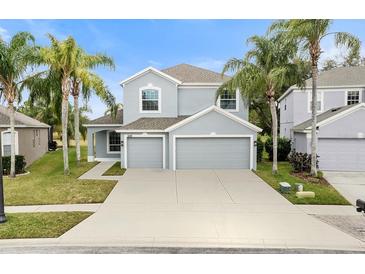 Two-story house with gray siding, three-car garage, and palm trees at 9856 Heron Pointe Dr, Orlando, FL 32832