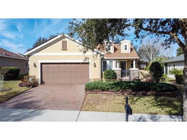 Well-maintained house with a brown garage door and brick driveway at 107 Cupania Ct, Groveland, FL 34736