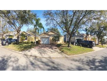 Cute yellow house with a white garage door and nicely landscaped yard at 1138 Mariner Cay Dr, Haines City, FL 33844