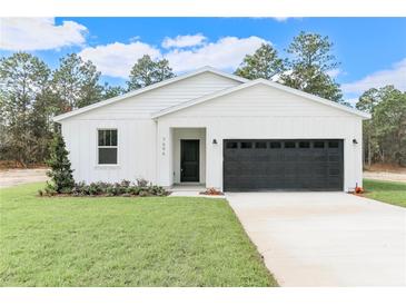 White farmhouse exterior with black garage door and landscaping at 12281 Sw 75Th St, Dunnellon, FL 34432