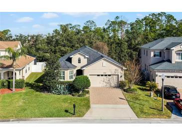 Single-Gathering home with two-car garage, manicured lawn, and brick driveway at 15925 St Clair St, Clermont, FL 34714