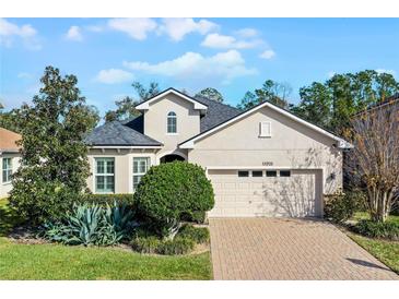 Two-story house with a beige exterior, gray roof, and a two-car garage at 15925 St Clair St, Clermont, FL 34714