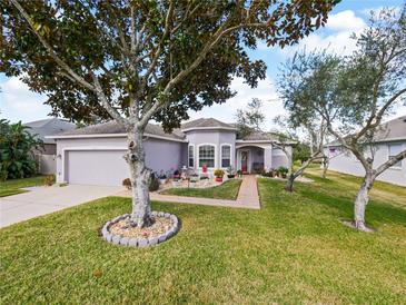 One-story home with gray exterior, landscaping, and a red door at 2446 Leaning Pine Ln, Oviedo, FL 32765