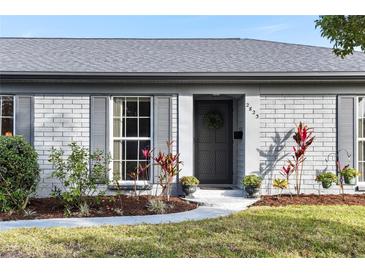 Charming home featuring a gray brick exterior, a welcoming front door, and professional landscaping at 2823 Cady Way, Winter Park, FL 32792