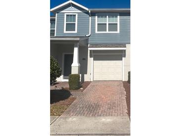 Two-story townhome with gray siding, white trim, and a brick paver driveway at 4126 Hedge Maple Pl, Winter Springs, FL 32708