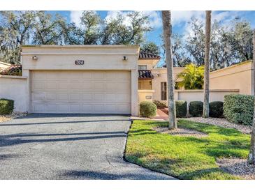 Tan stucco home with a two-car garage and lush landscaping at 706 Santa Cruz Ln, Howey In The Hills, FL 34737