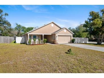 One-story house with tan exterior, front porch, and landscaped yard at 110 Oak St, Clermont, FL 34711