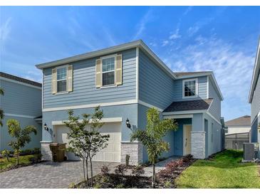 Two-story house with light blue siding, two-car garage, and a landscaped front yard at 1611 Kona Ln, Davenport, FL 33897