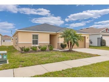 Beige house with gray roof, palm tree, and a two-car garage at 213 Lake Lucerne Way, Winter Haven, FL 33881