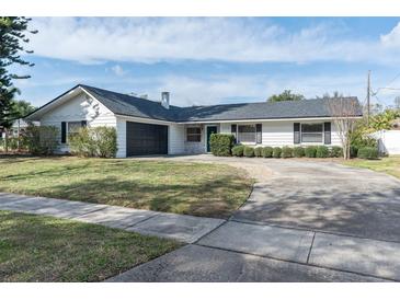 White house with black garage door, landscaping, and long driveway at 2779 Prince John Rd, Winter Park, FL 32792