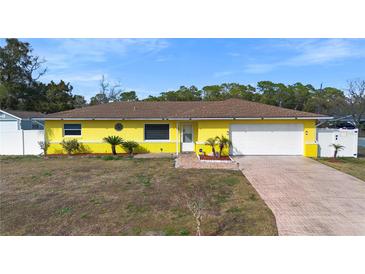 Charming yellow home featuring a one-car garage, a well-maintained lawn, and tidy landscaping at 40 Lantana Dr, Debary, FL 32713