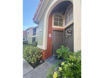 Inviting condo entrance with landscaping and a charming brown door at 429 Fountainhead Cir # 122, Kissimmee, FL 34741